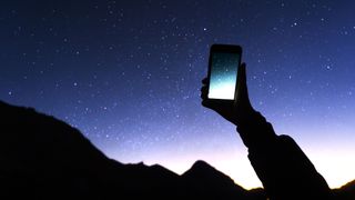 Best stargazing apps: Image shows person holding mobile up to starry night sky